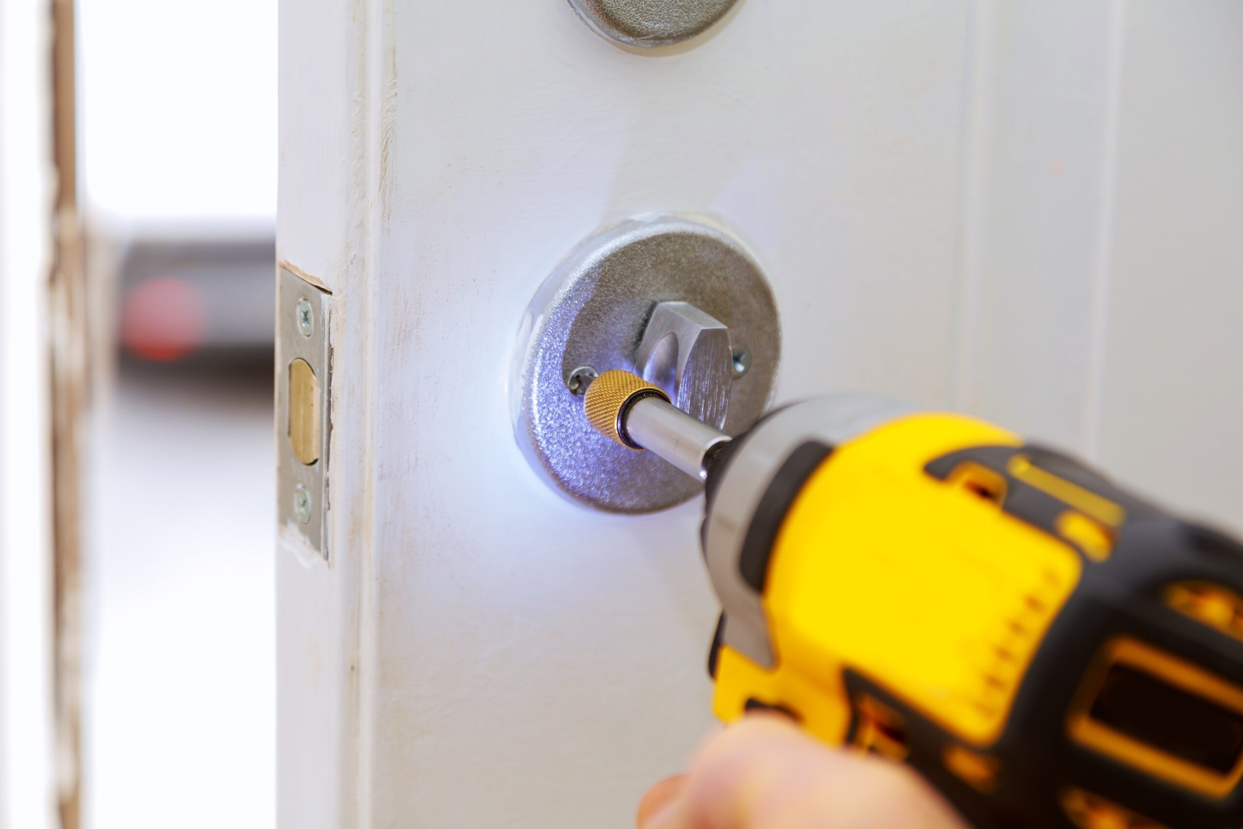 Closeup of a professional locksmith installing a new lock on a house exterior door with the inside internal parts of the lock